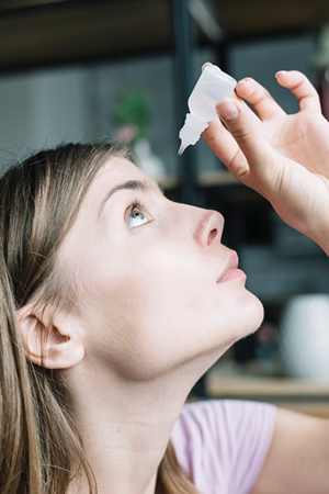 woman putting in eye drops