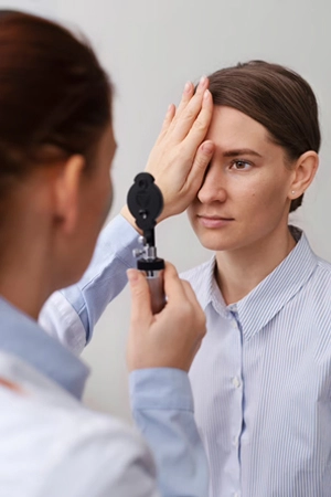 a woman doctor looking into a woman patient's eye with a eye device