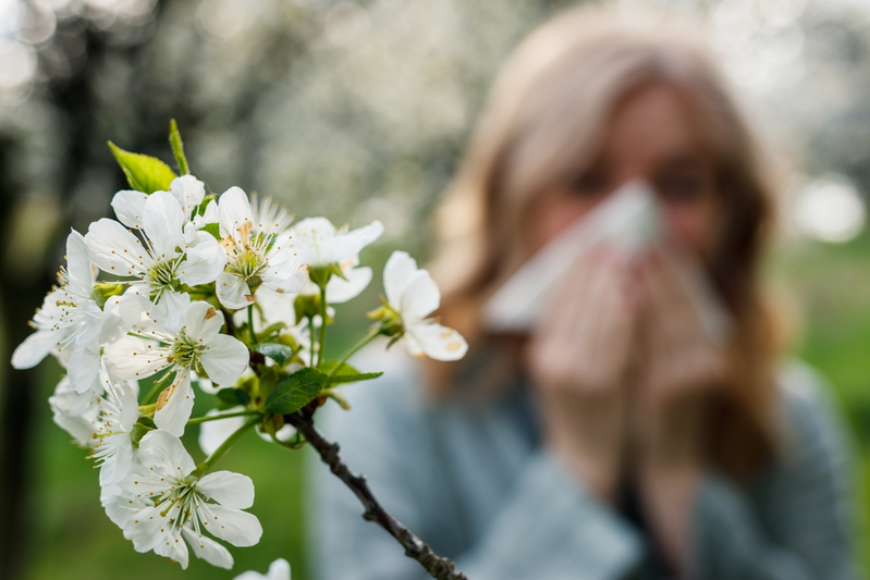 woman sneezing next to flower